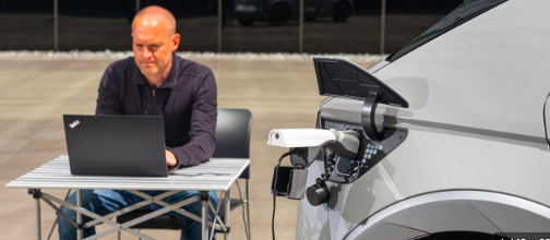 Man using a laptop which is being powered from a Hyundai IONIQ 5 electric vehicle,